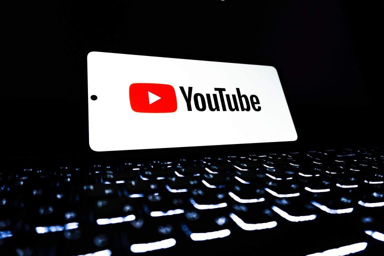 Logo de YouTube sobre una computadora portátil con teclado iluminado, imagen ilustrativa de la plataforma de videos.